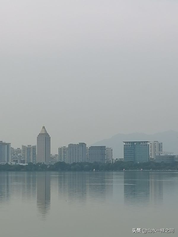 湖水淡淡如镜，倒映天光云影，微风轻拂，碧波轻漾，宛如一幅静谧悠远的水墨丹青。