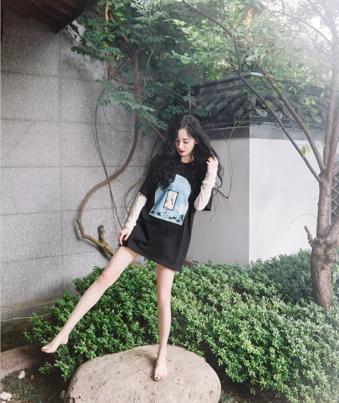 杨幂的这身夏天的穿搭是经典的"下衣失踪"风格,上身一件宽大的黑色t恤