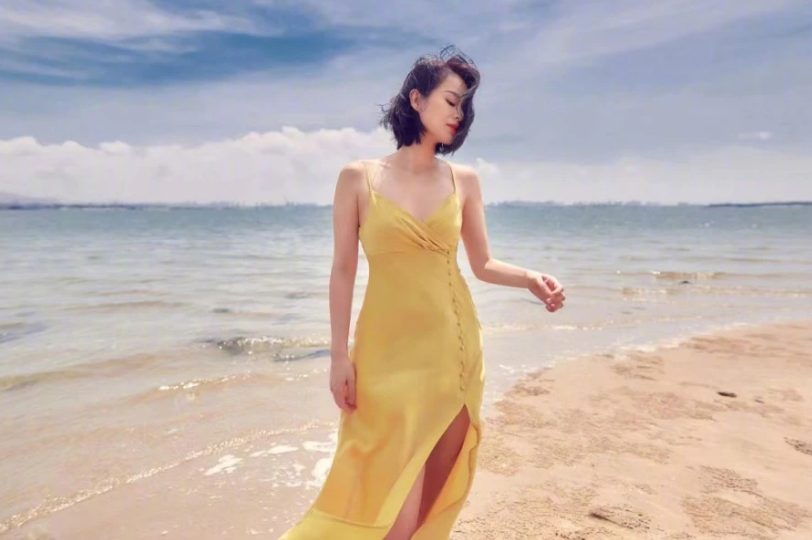 41岁胡杏儿穿吊带炫身材，光脚丫站海水中，裙子开叉秀一侧大长腿