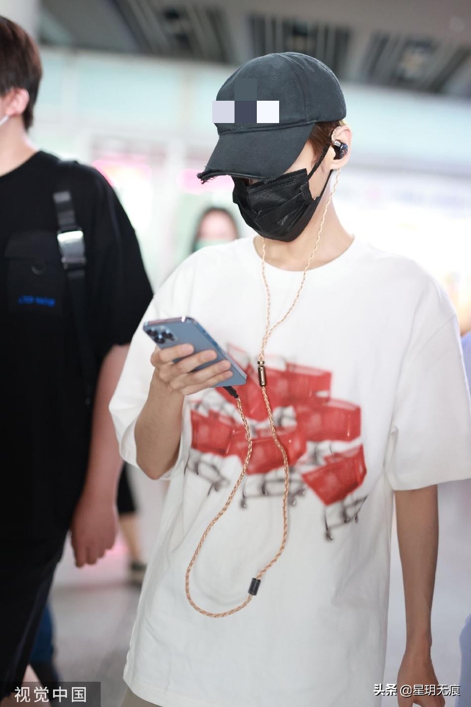 罗云熙机场一路看手机前行 穿白色T恤搭大短裤清爽干净