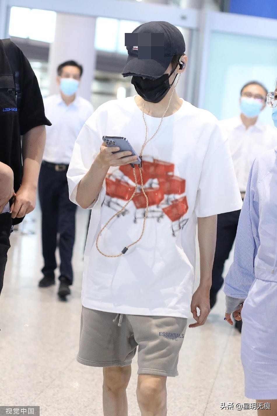 罗云熙机场一路看手机前行 穿白色T恤搭大短裤清爽干净