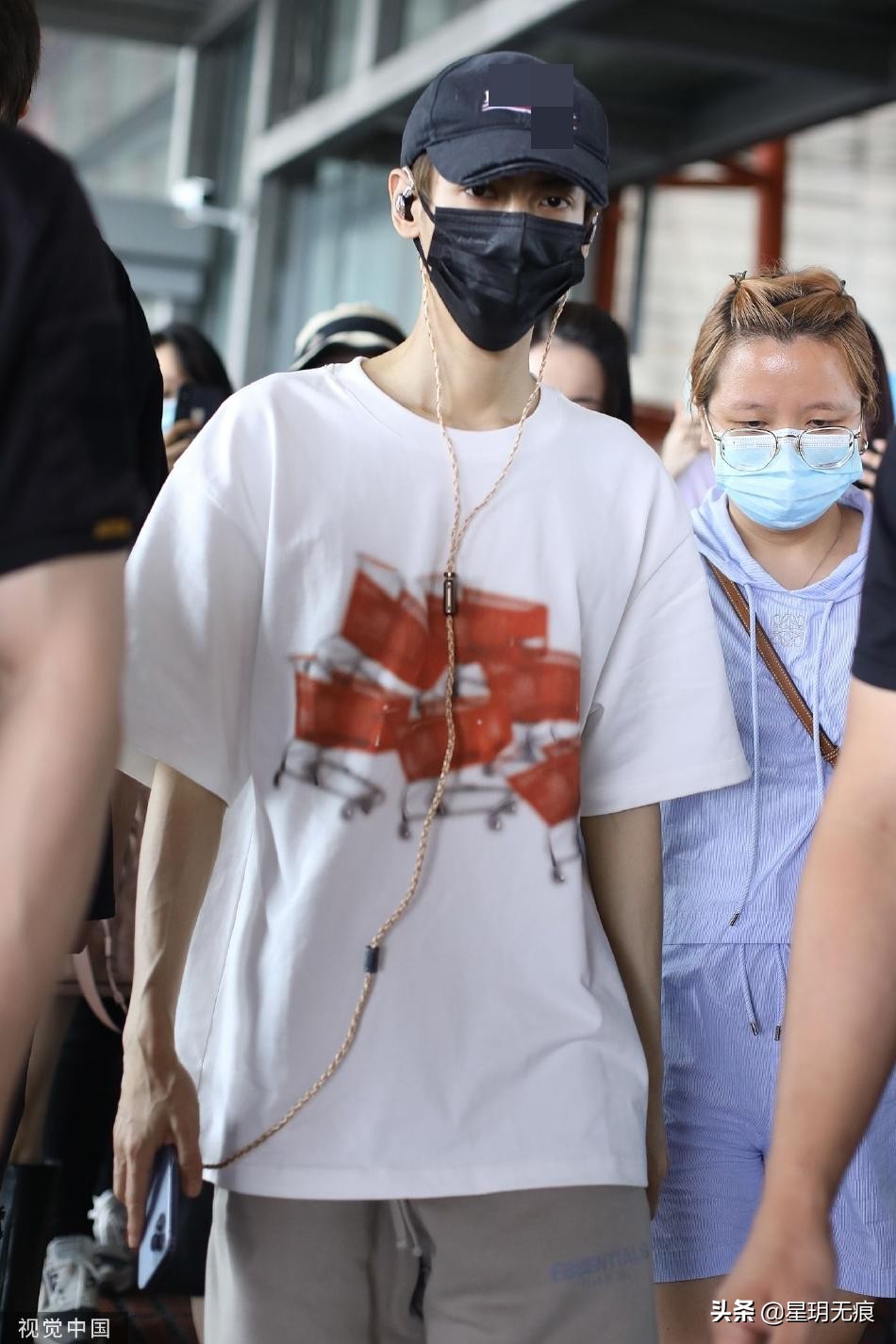 罗云熙机场一路看手机前行 穿白色T恤搭大短裤清爽干净