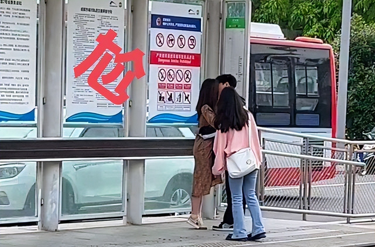 情侣车站下拥吻回顾，女生路过驻足观看，情侣一脸尴尬，捂脸苦笑