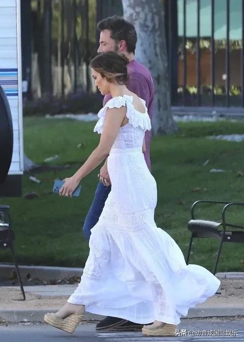 詹妮弗洛佩兹身着飘逸的白色礼服与未婚夫手牵手走在片场上